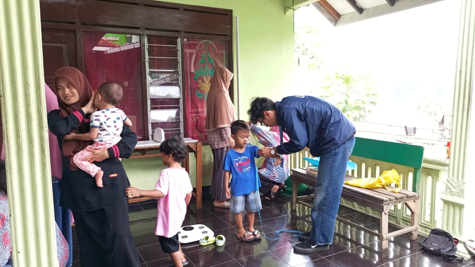 Mahasiswa KKN UPGRIS Dukung Pelaksanaan Posyandu dan Posbindu RW 1 Kelurahan Genuk 1 A person standing next to a group of children AI-generated content may be incorrect.
